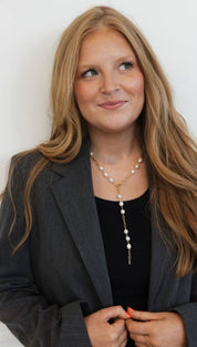 A delicate gold chain necklace adorned with a series of white pearls and a small metallic pendant.