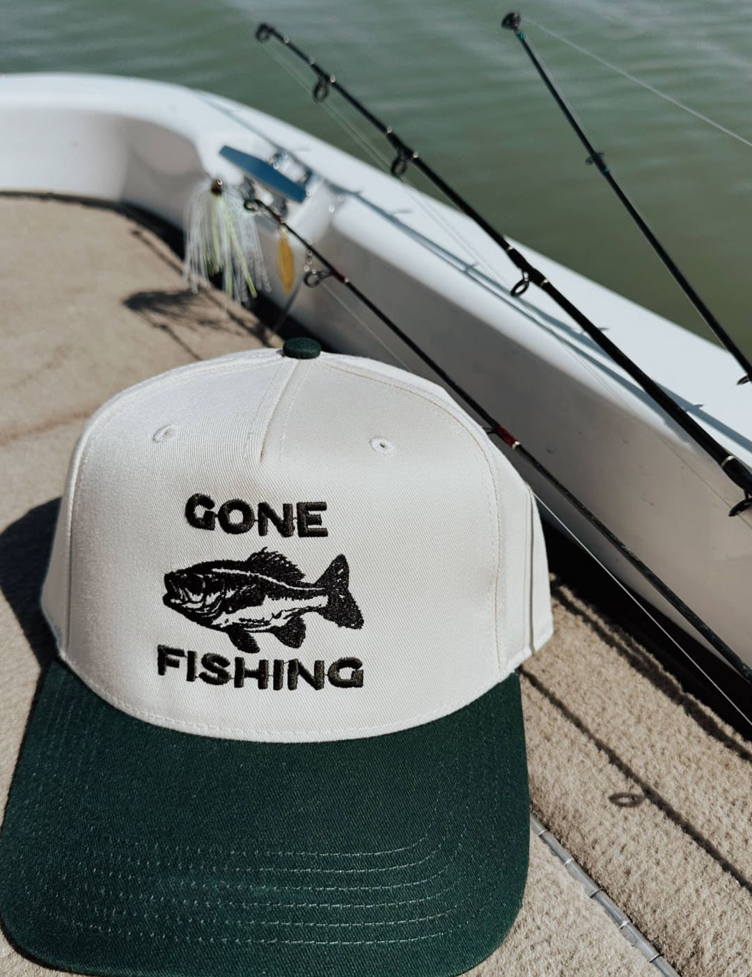 White and green two-tone baseball cap with black embroidered ’gone fishing’ text and fish graphic.