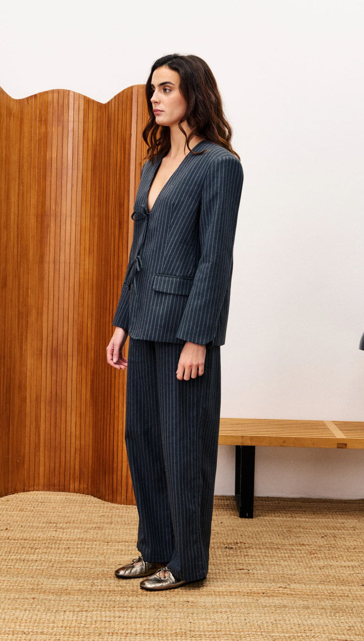A woman in a pinstriped suit with a deep V-neck jacket and matching trousers.