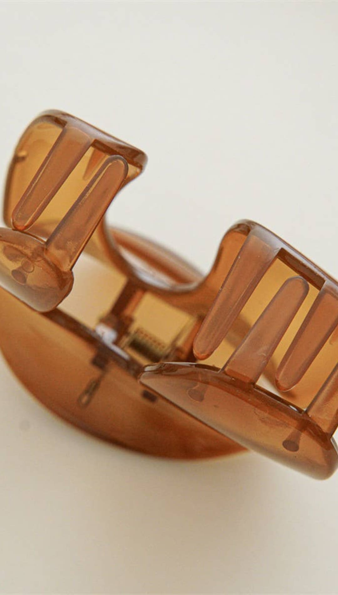 Amber plastic claw hair clip with curved prongs and translucent finish.