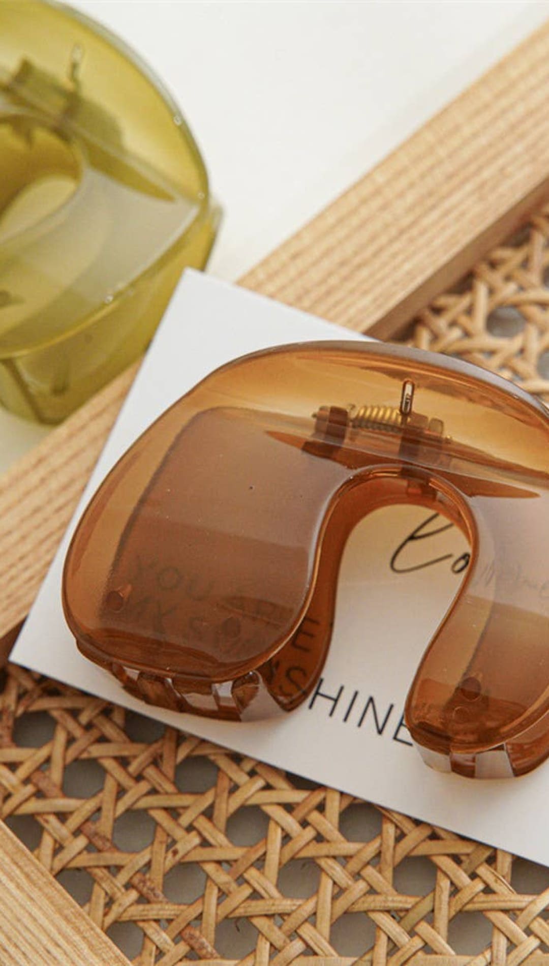 Brown translucent plastic hair clip with spring mechanism and small screw detail, likely from a popular brand known for accessories.