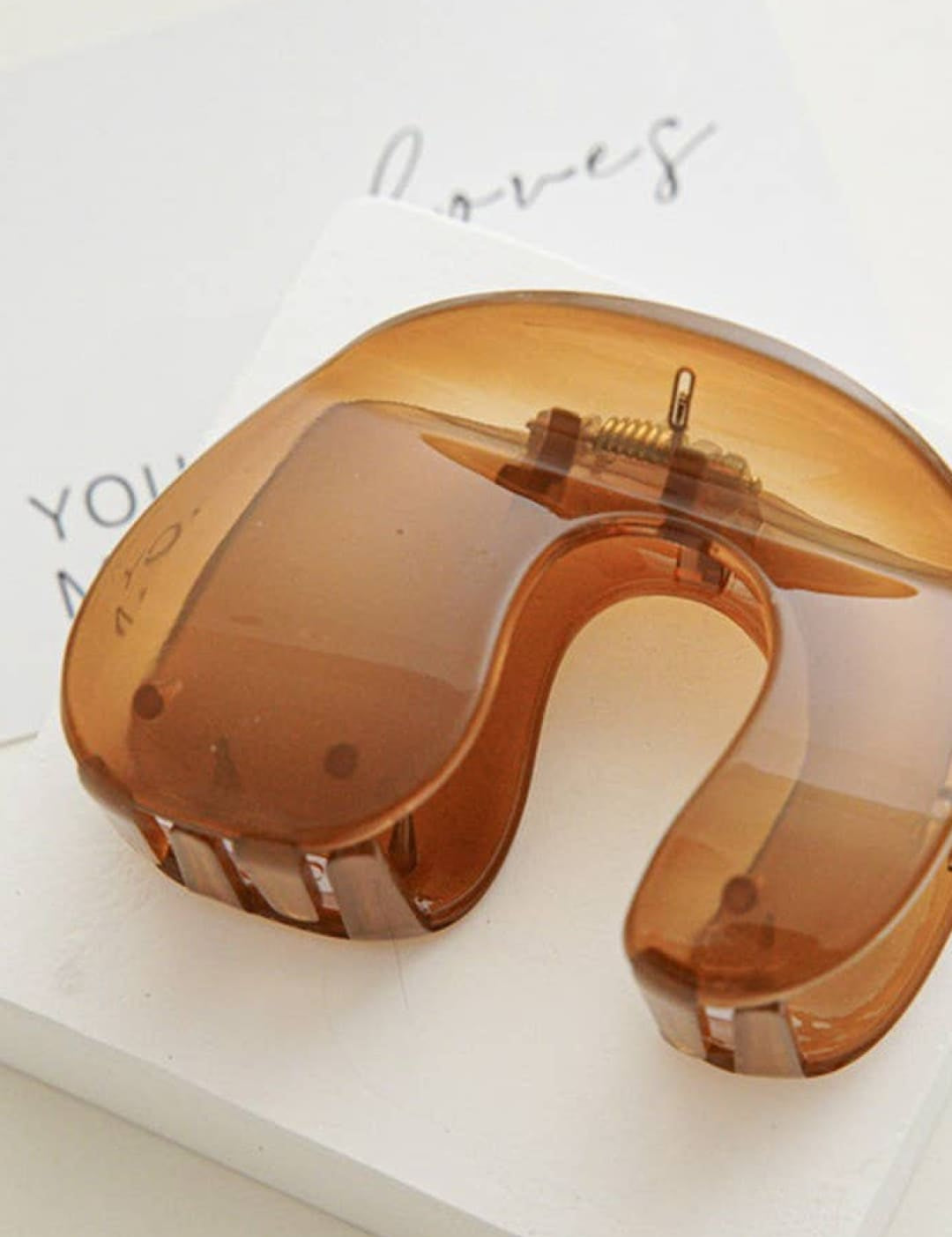 Amber-colored plastic neck pillow with rose gold accents and a minimalist design.