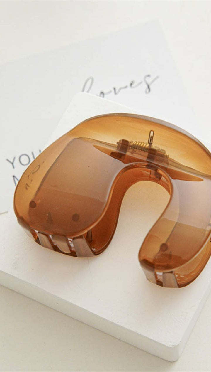 Amber-colored plastic neck pillow with rose gold accents and a minimalist design.