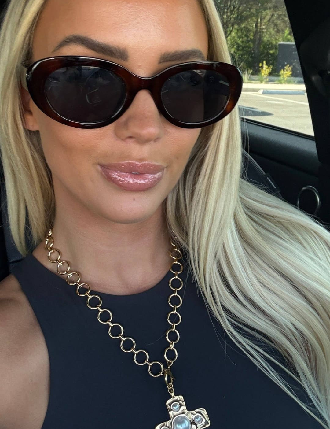 Gold chain necklace with a cross pendant featuring a central blue stone and smaller clear stones.