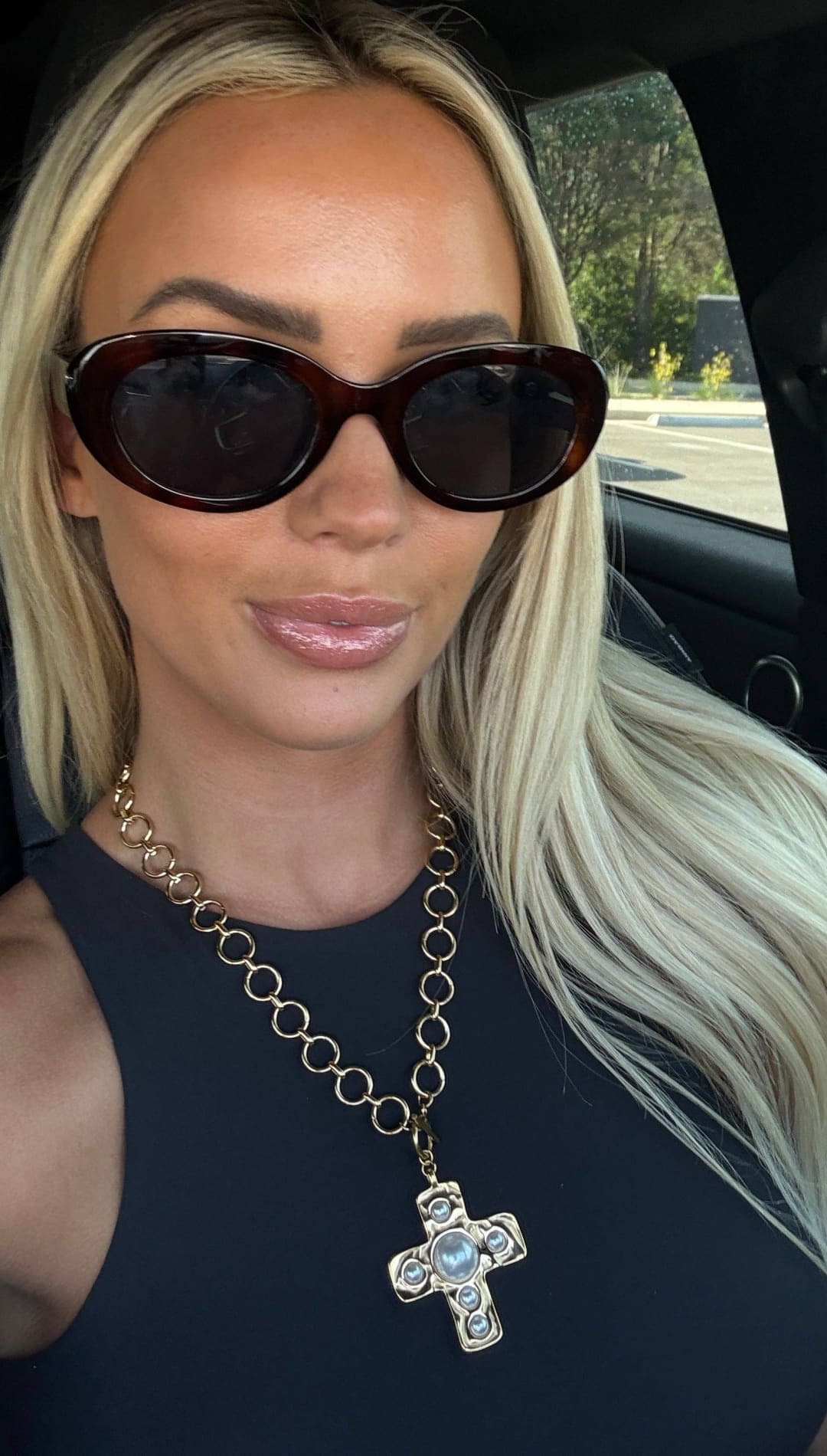 Gold chain necklace with a cross pendant featuring a central blue stone and smaller clear stones.