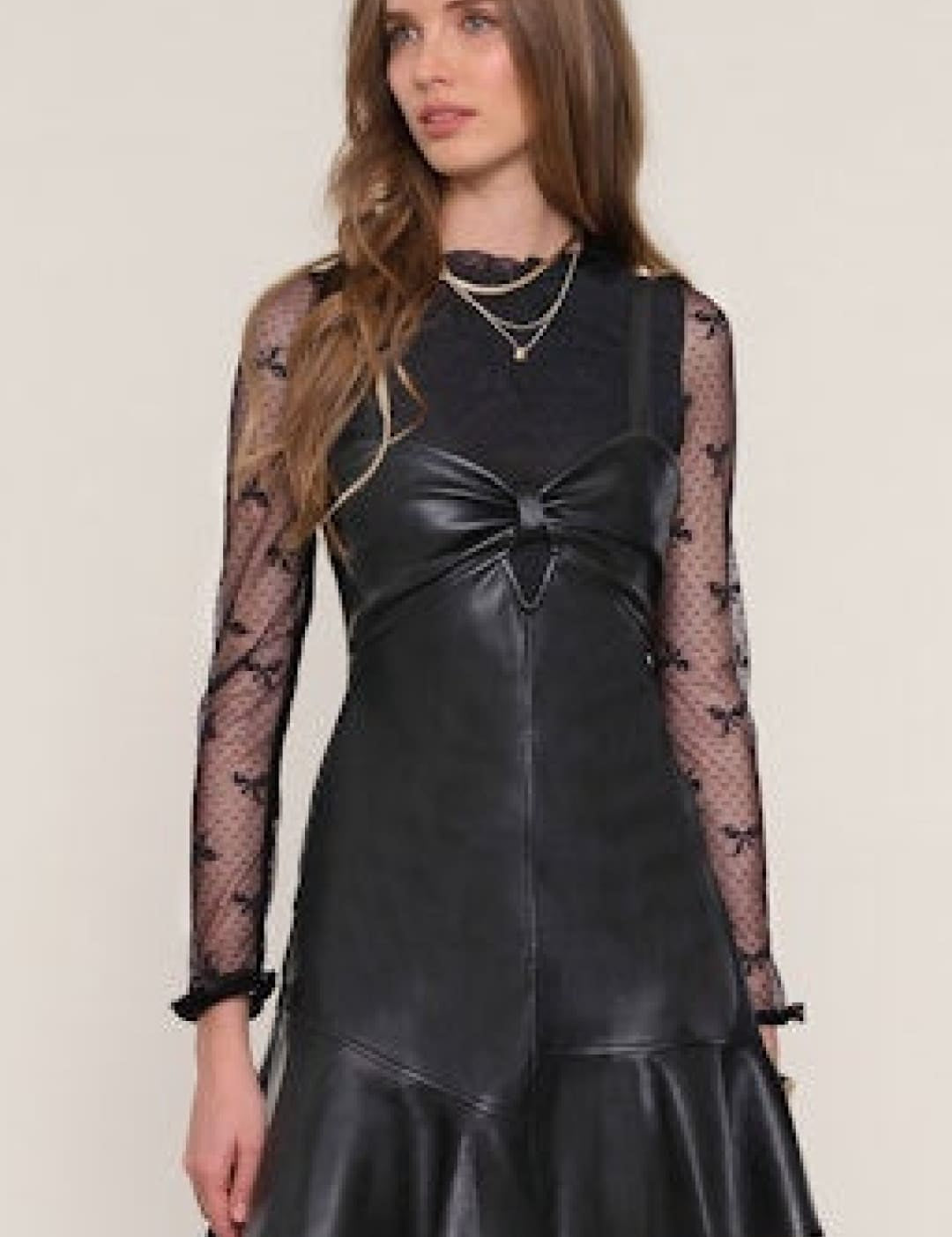 Black faux leather mini dress with a sheer long-sleeved top.