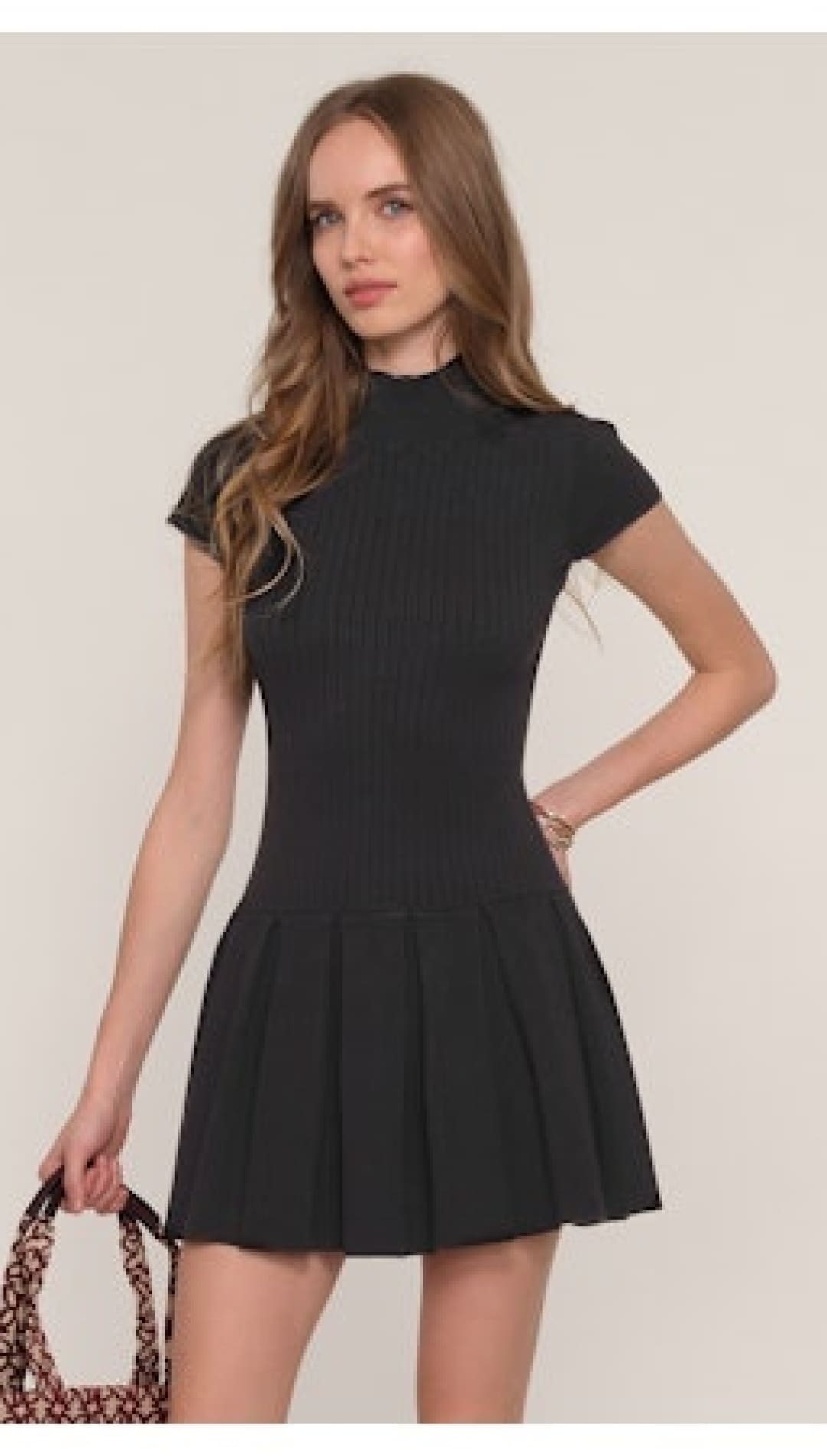 A black short-sleeved mock-neck mini dress with a pleated skirt.