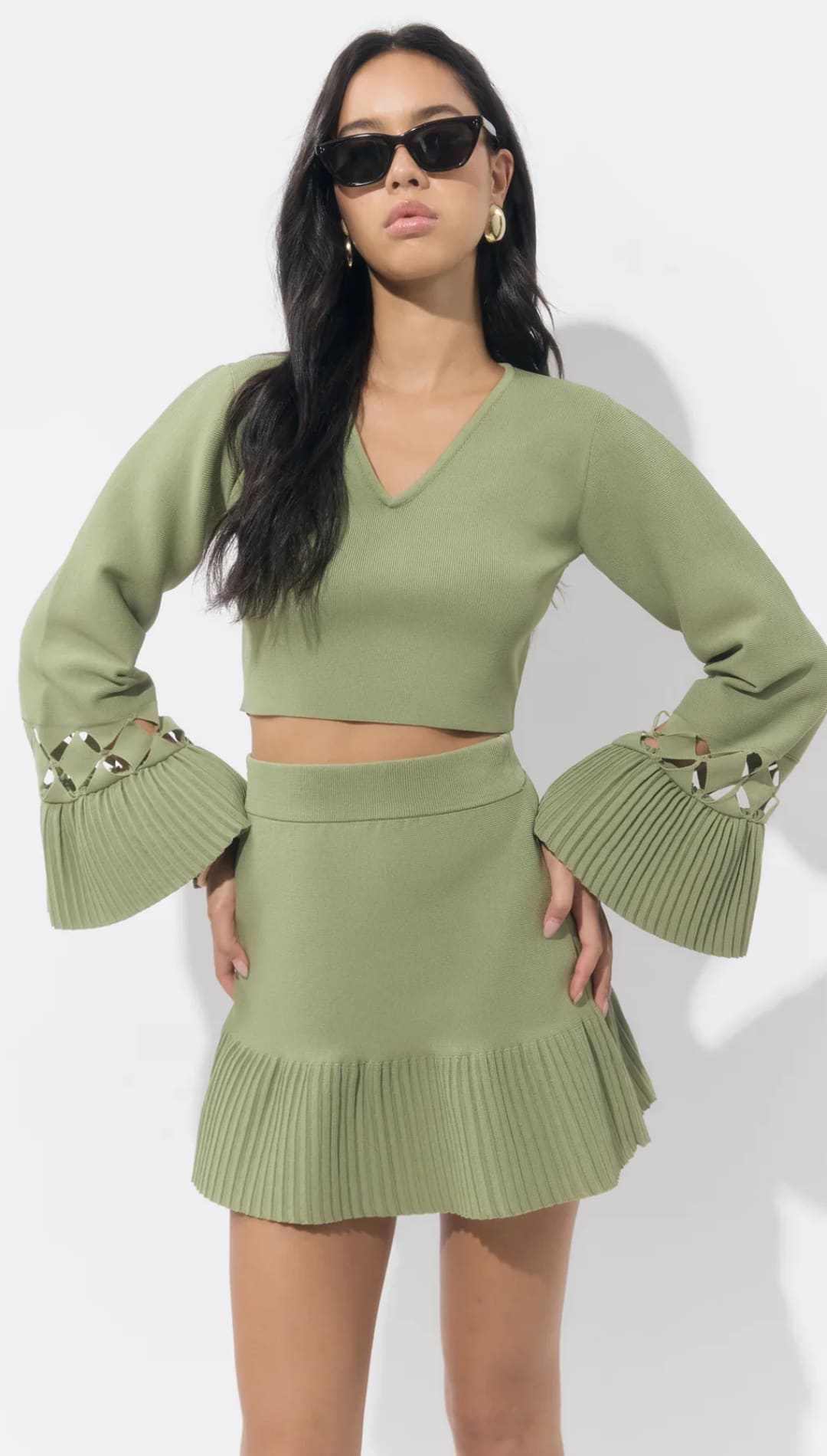 Olive green knit crop top and skirt set with bell sleeves, featuring a fringed hem.