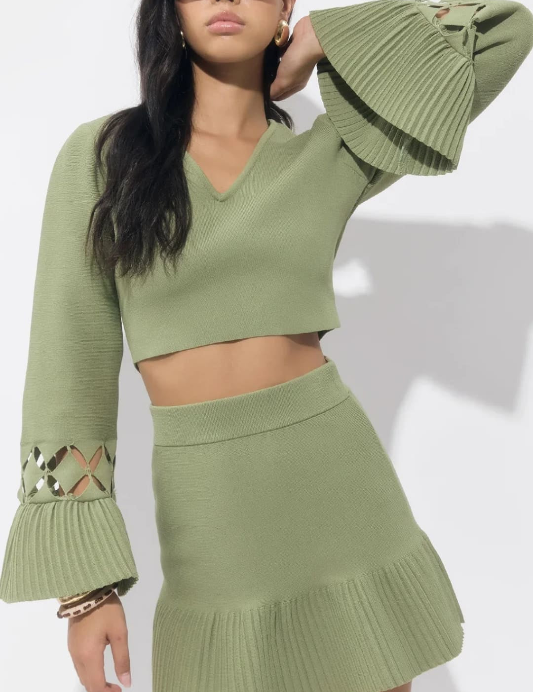 Olive green knit crop top with bell sleeves and sequin detail, paired with a matching mini skirt.