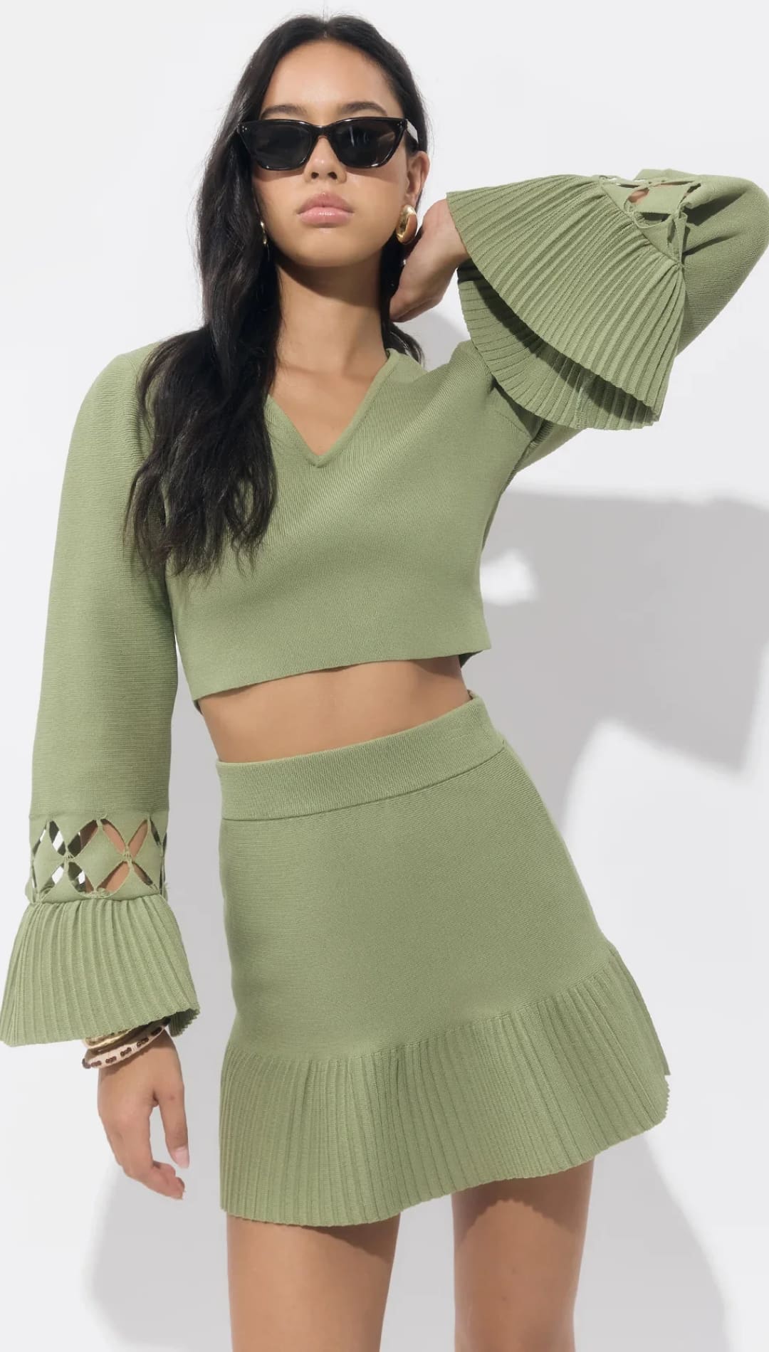 Olive green knit crop top with bell sleeves and sequin detail, paired with a matching mini skirt.
