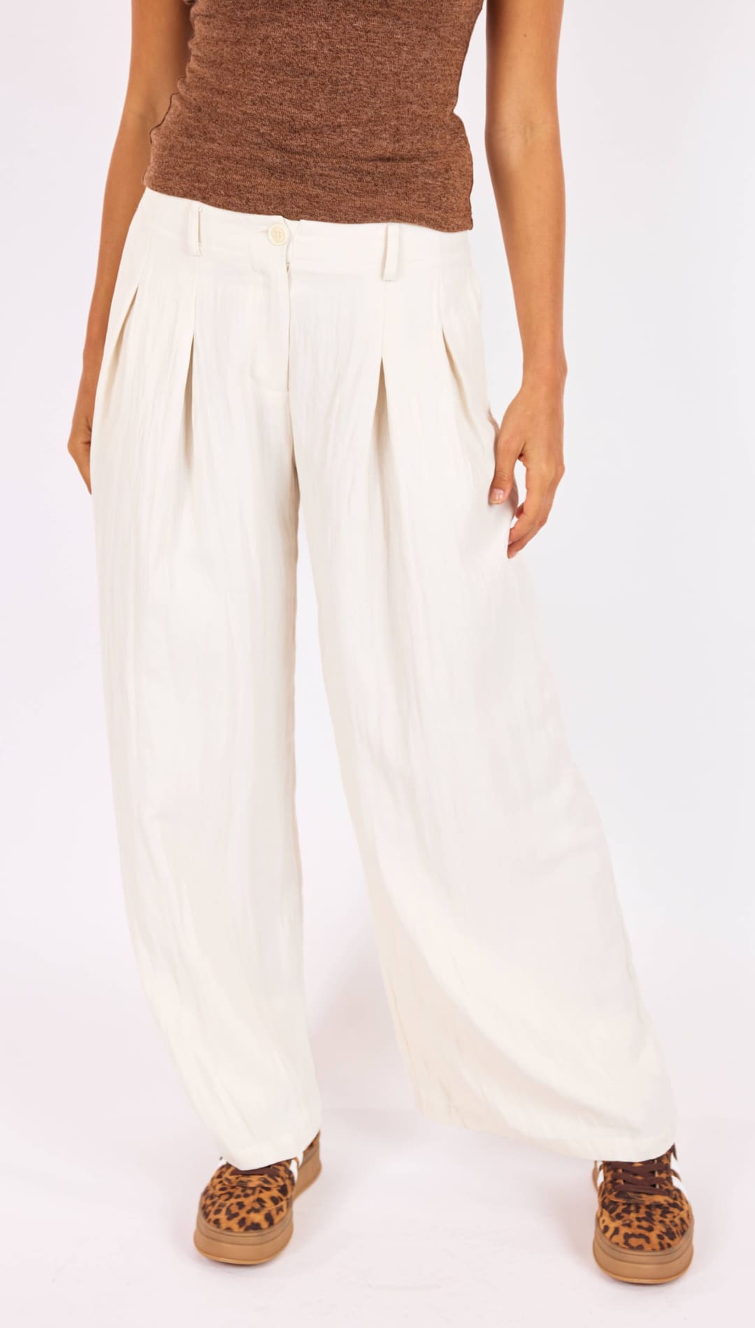 Cream-colored, high-waisted pleated trousers with a relaxed fit.