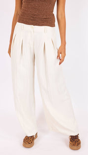 Cream-colored, high-waisted pleated trousers with a relaxed fit.