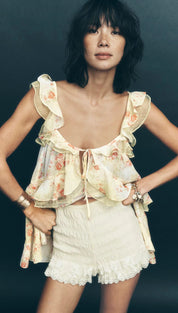 Floral ruffled summer top with cream and light yellow hues, featuring a tie at the neckline.