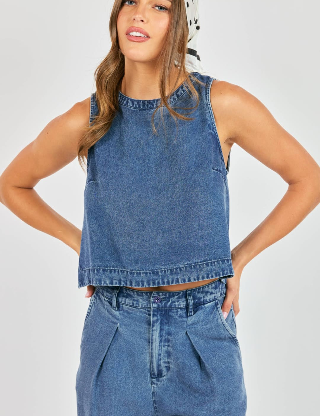 Blue denim sleeveless crop top with a round neckline and frayed hem
