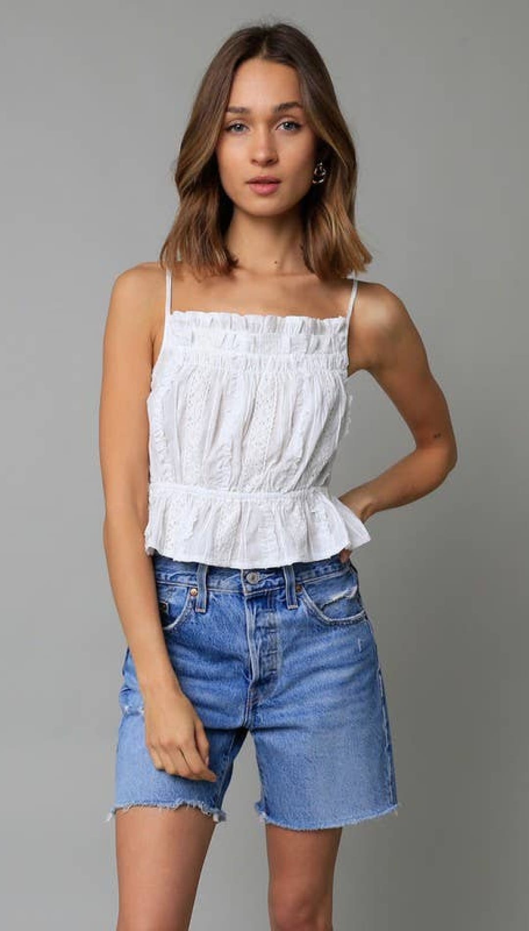 White embroidered smocked camisole top with ruffled hem and thin straps.