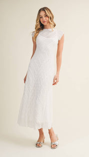 A flowing white lace midi dress with a fitted bodice and sheer cap sleeves.