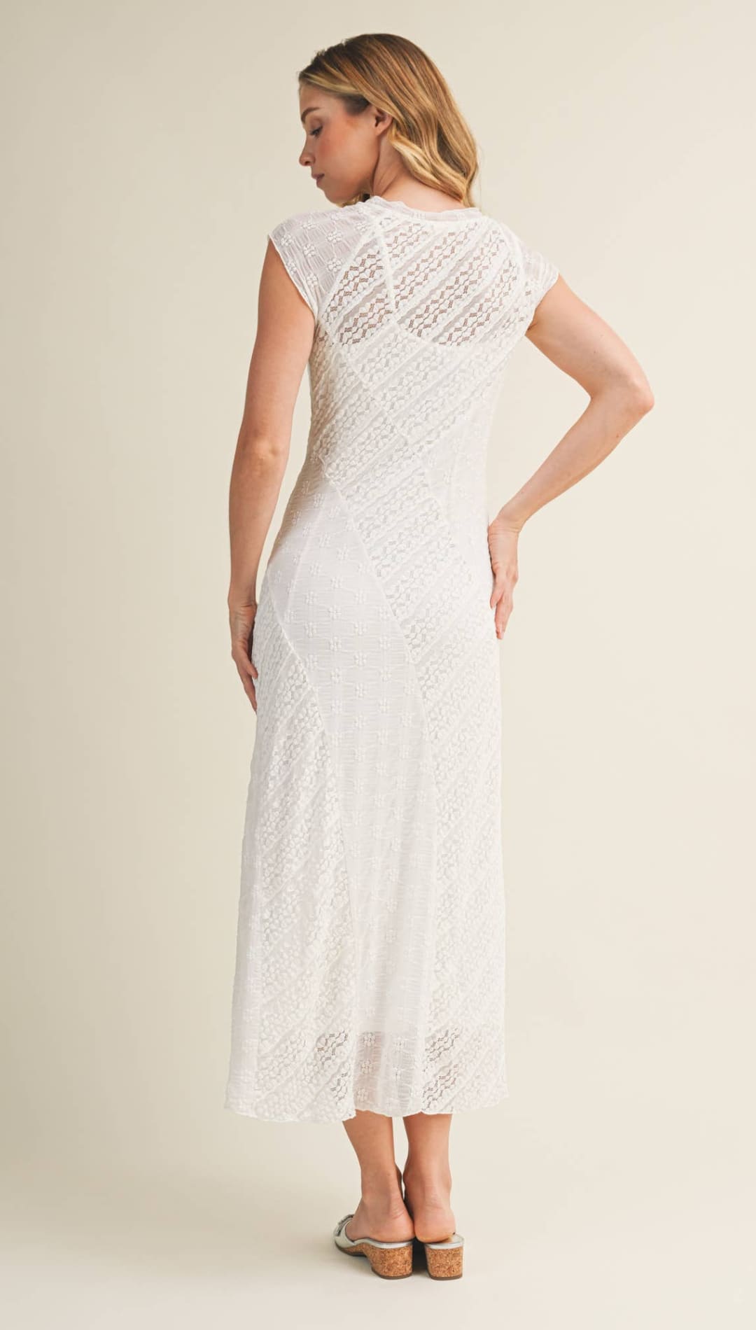A white lace maxi dress with a fitted bodice and flowing skirt, featuring delicate floral patterns throughout.