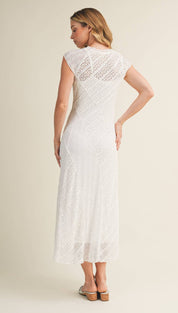 A white lace maxi dress with a fitted bodice and flowing skirt, featuring delicate floral patterns throughout.