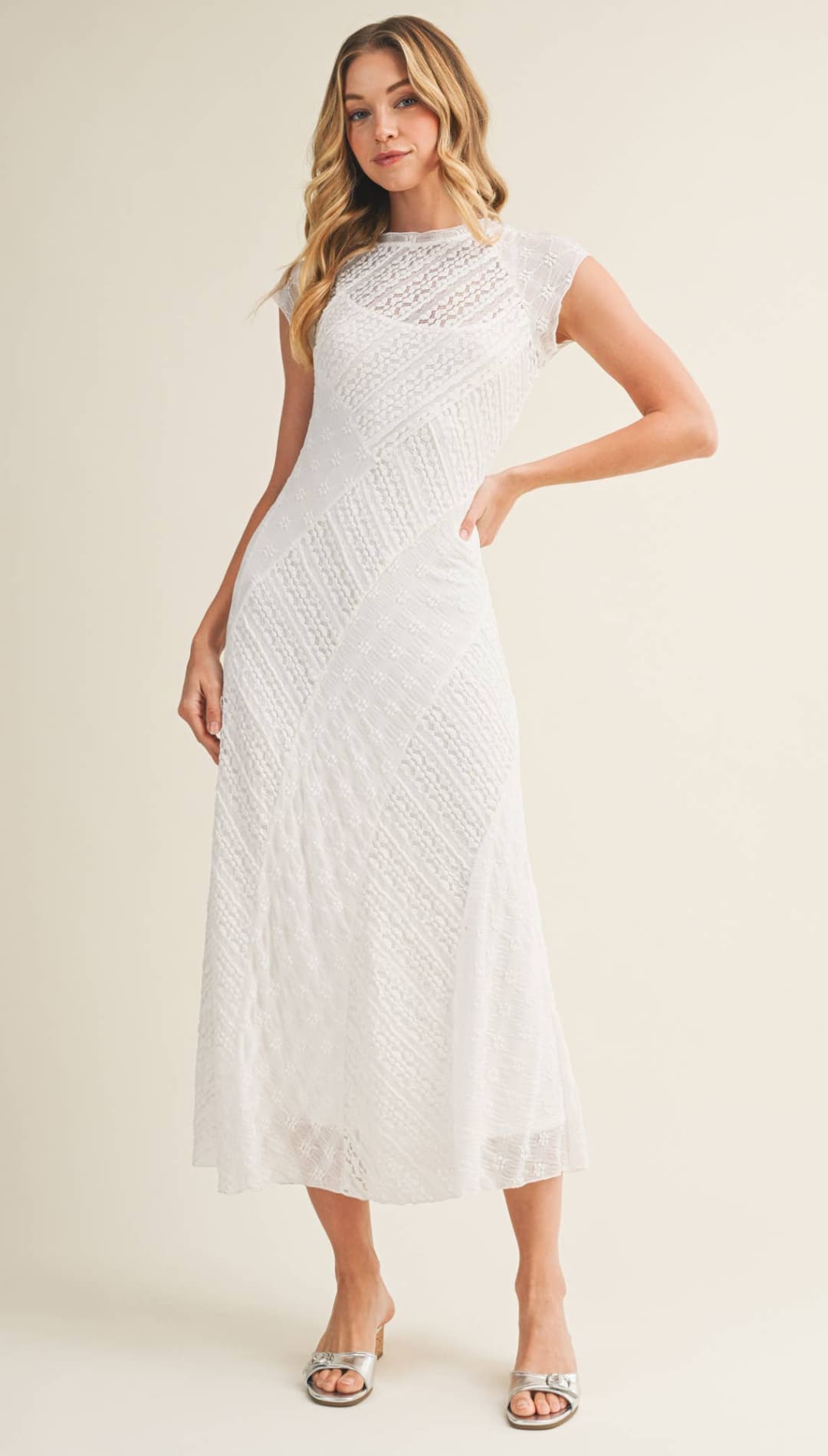 A white lace midi dress with a fitted bodice and flowing skirt.