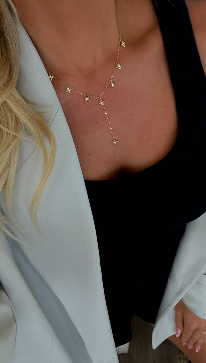 A delicate gold chain necklace adorned with small, star-shaped pendants that drape elegantly across the collarbone.