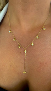 A delicate gold chain necklace adorned with small, sparkling diamond-studded star-shaped pendants arranged in a v-shape that gracefully drapes down the center of the chest.