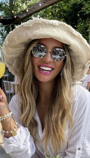 Smiling woman in a floppy hat and sunglasses.