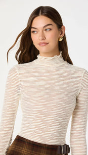 A cream-colored, long-sleeved turtleneck top with a subtle horizontal striped texture.