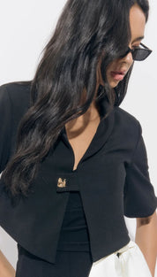 A woman wearing a black bolero jacket with a gold brooch.