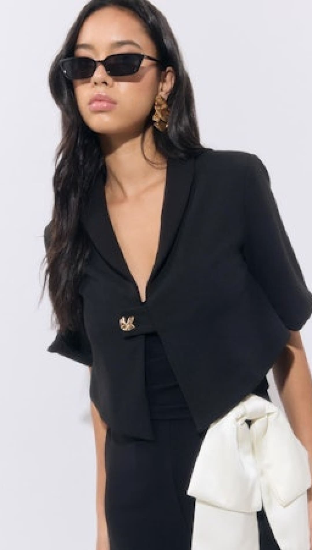 Black cropped blazer with a gold brooch and wide lapels.