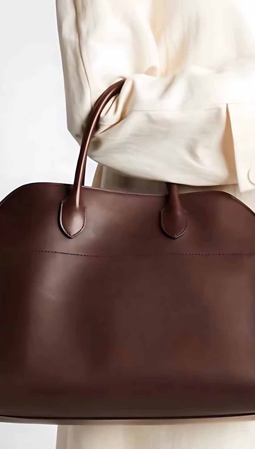 Brown leather tote bag with a structured shape and adjustable strap.