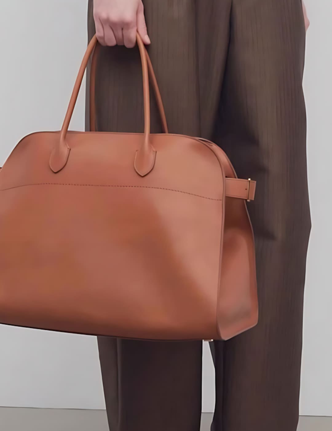 Brown leather tote bag with tan handles and a structured design.