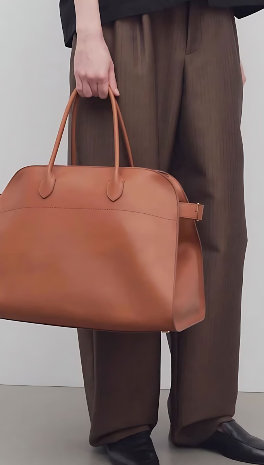 Brown leather tote bag with tan handles and a structured design.