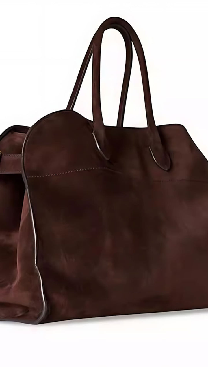 Brown leather tote bag with long handles and a buckle detail.