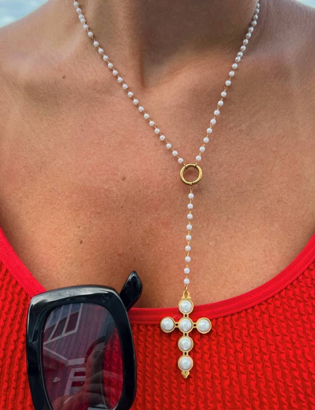 A delicate pearl and gold cross necklace with a y-shaped chain design.