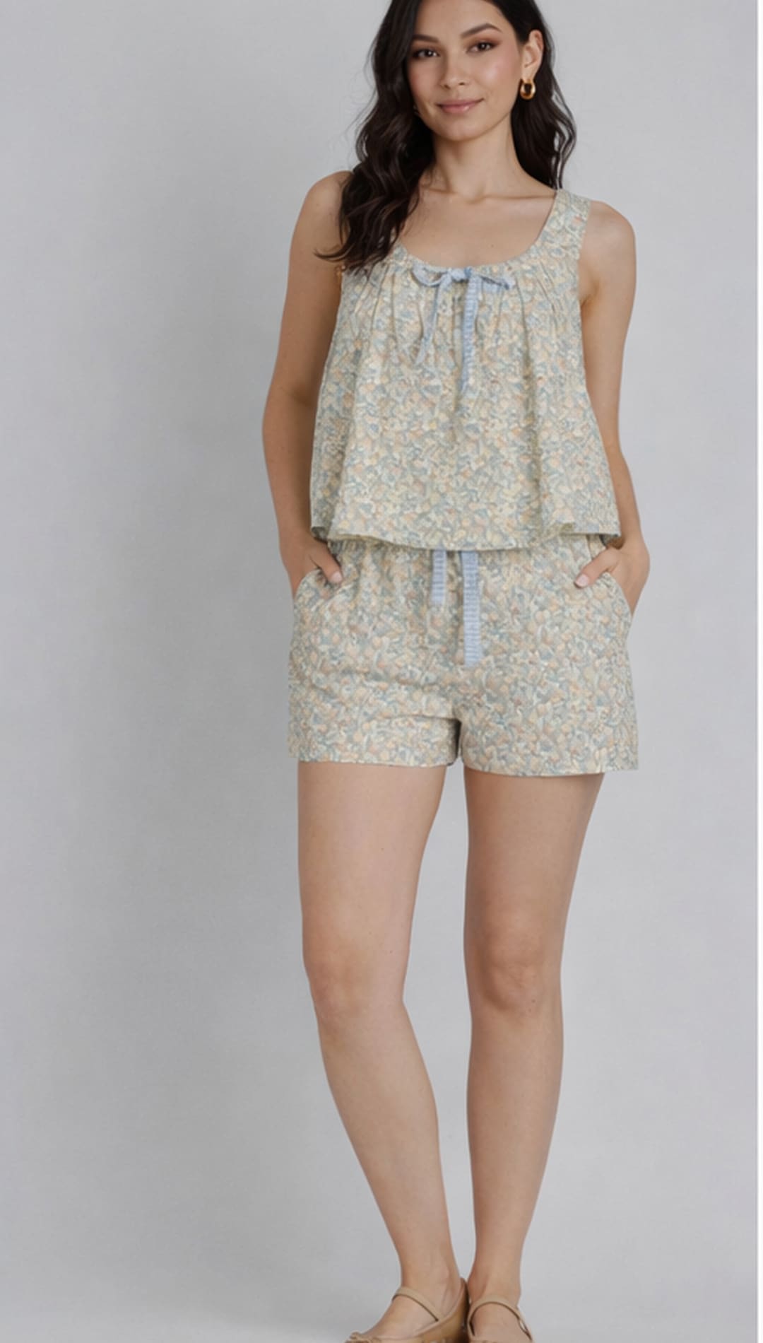 A light green floral print romper with a ruffled top and drawstring waist.