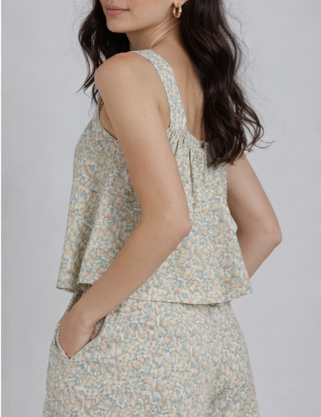 A soft, light green and white floral print sleeveless top with a ruffled hemline.