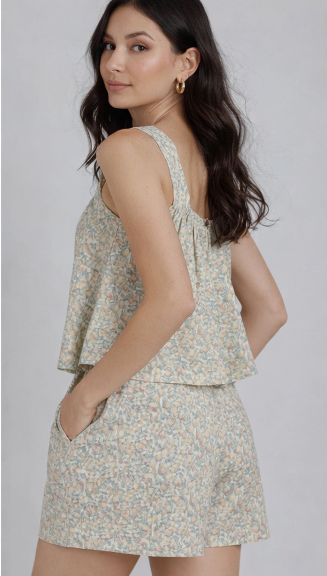 A soft, light green and white floral print sleeveless top with a ruffled hemline.