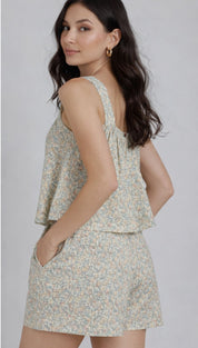 A soft, light green and white floral print sleeveless top with a ruffled hemline.