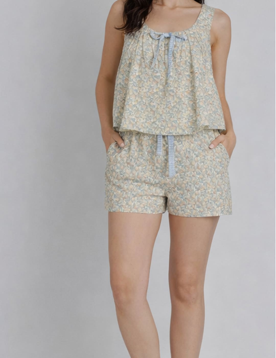 A soft, light green floral print two-piece loungewear set with a ruffled top and matching shorts featuring a drawstring waist.