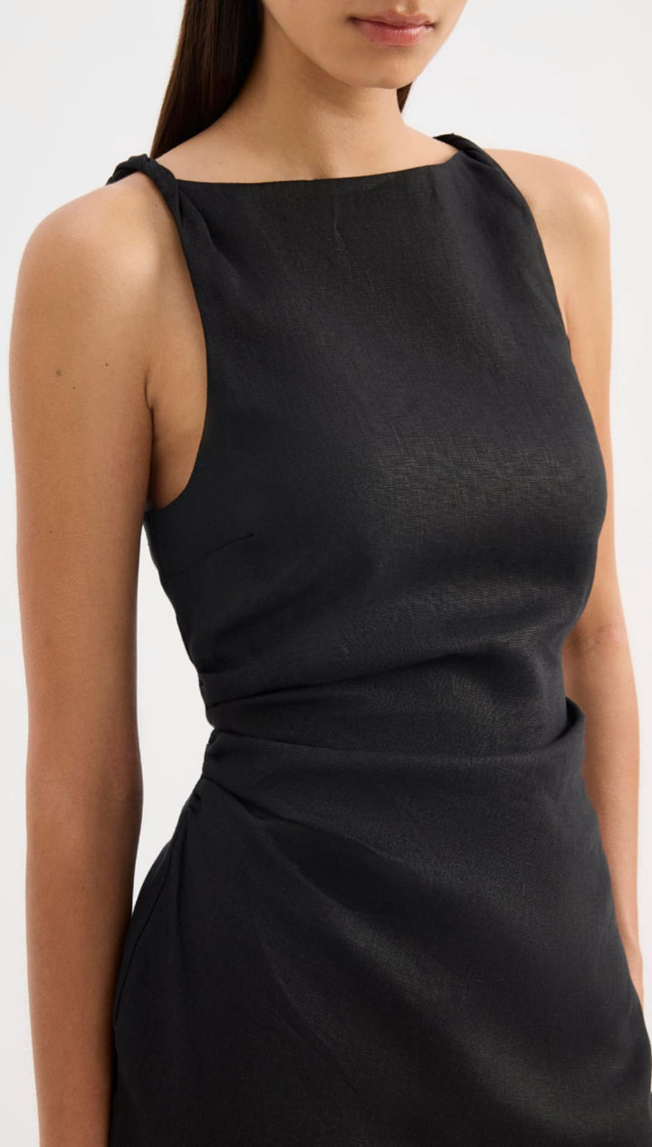 Black sleeveless dress with a draped waistline and soft, flowing fabric.