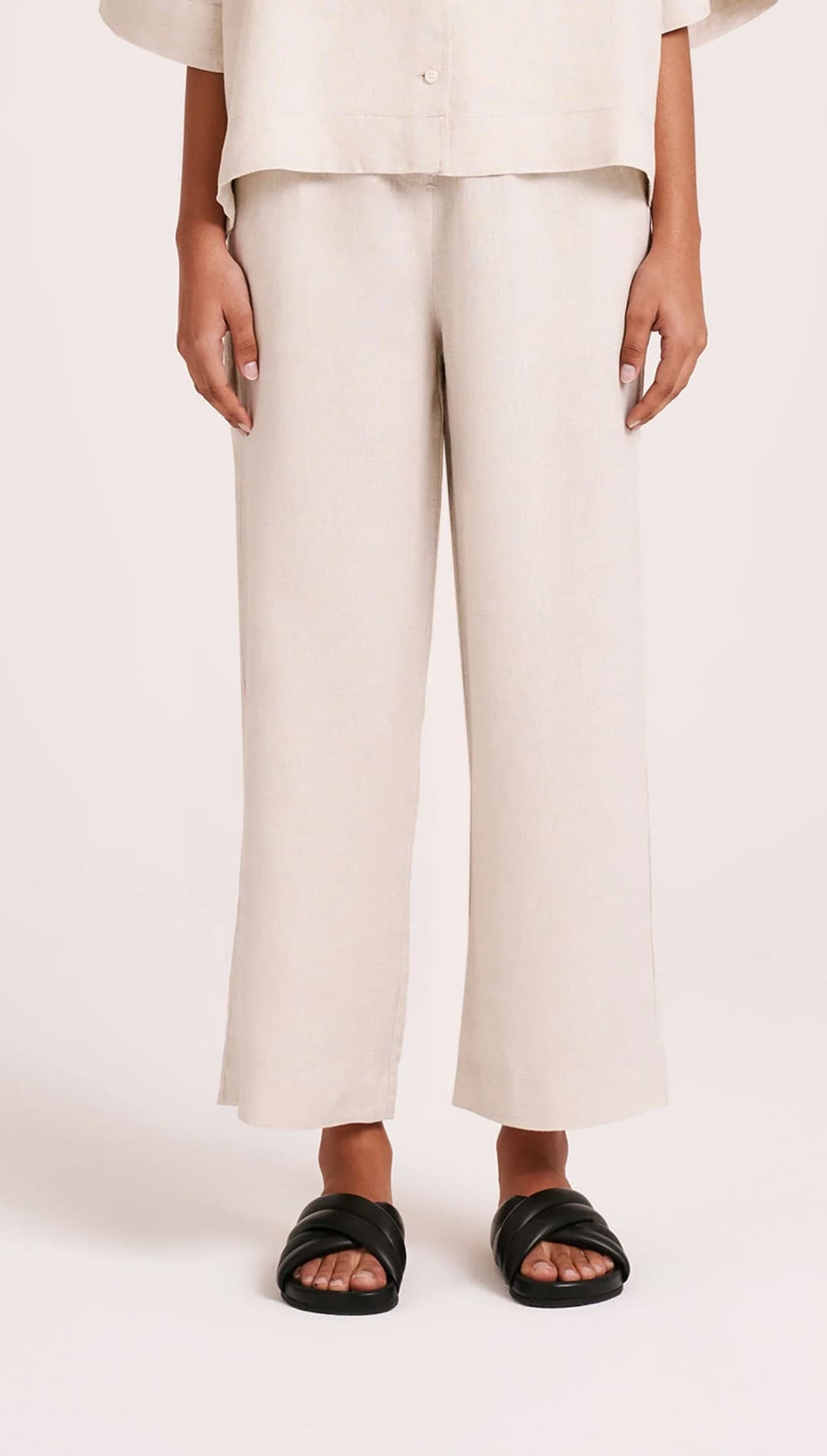 Beige linen pants with black sandals.