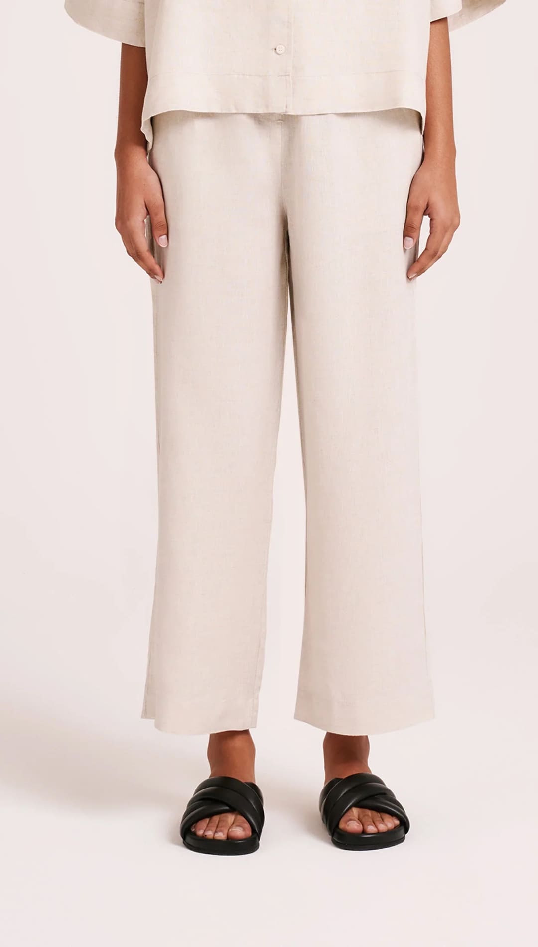 Beige linen pants with black sandals.