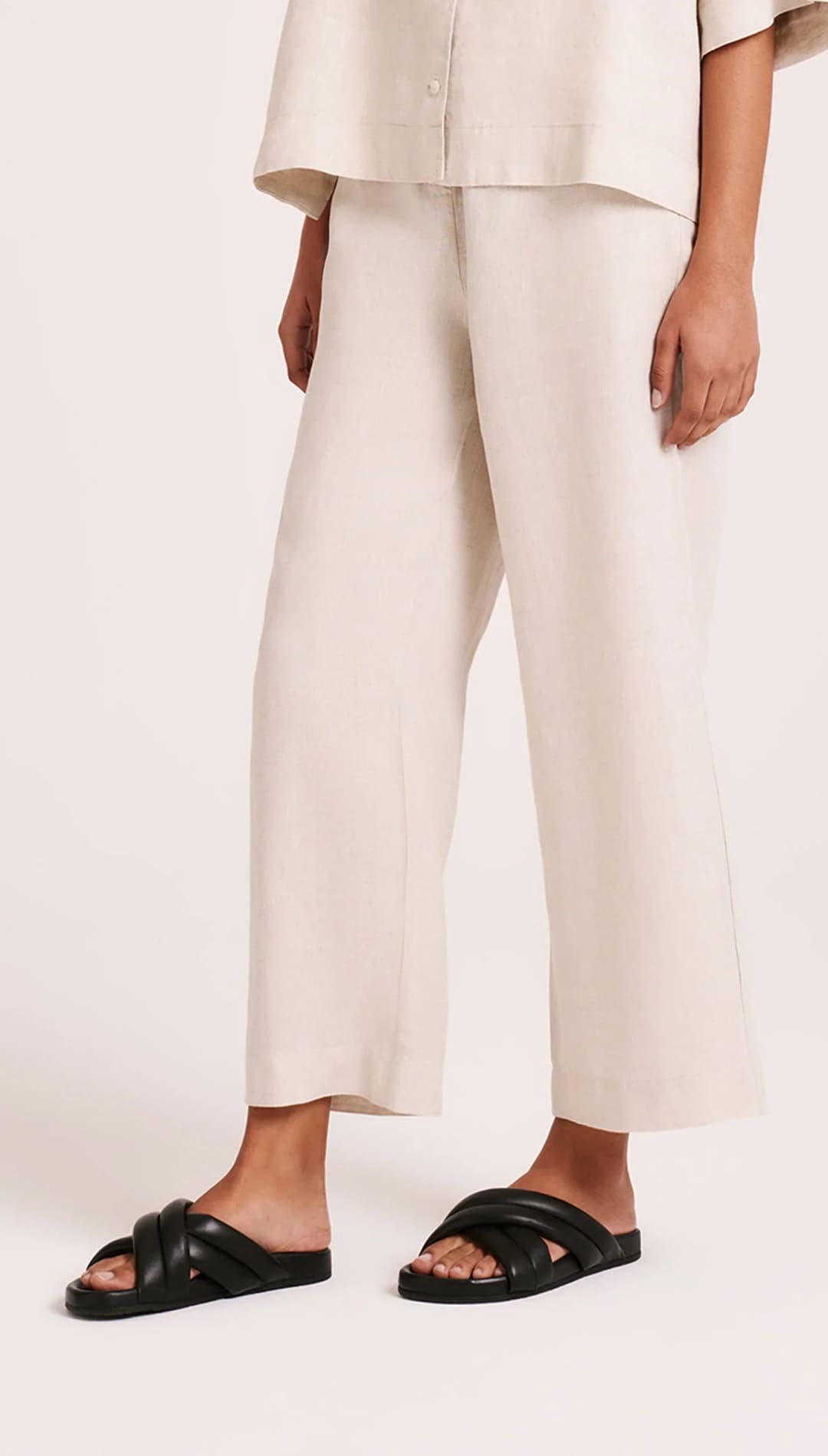 Beige wide-leg pants with black criss-cross sandals.