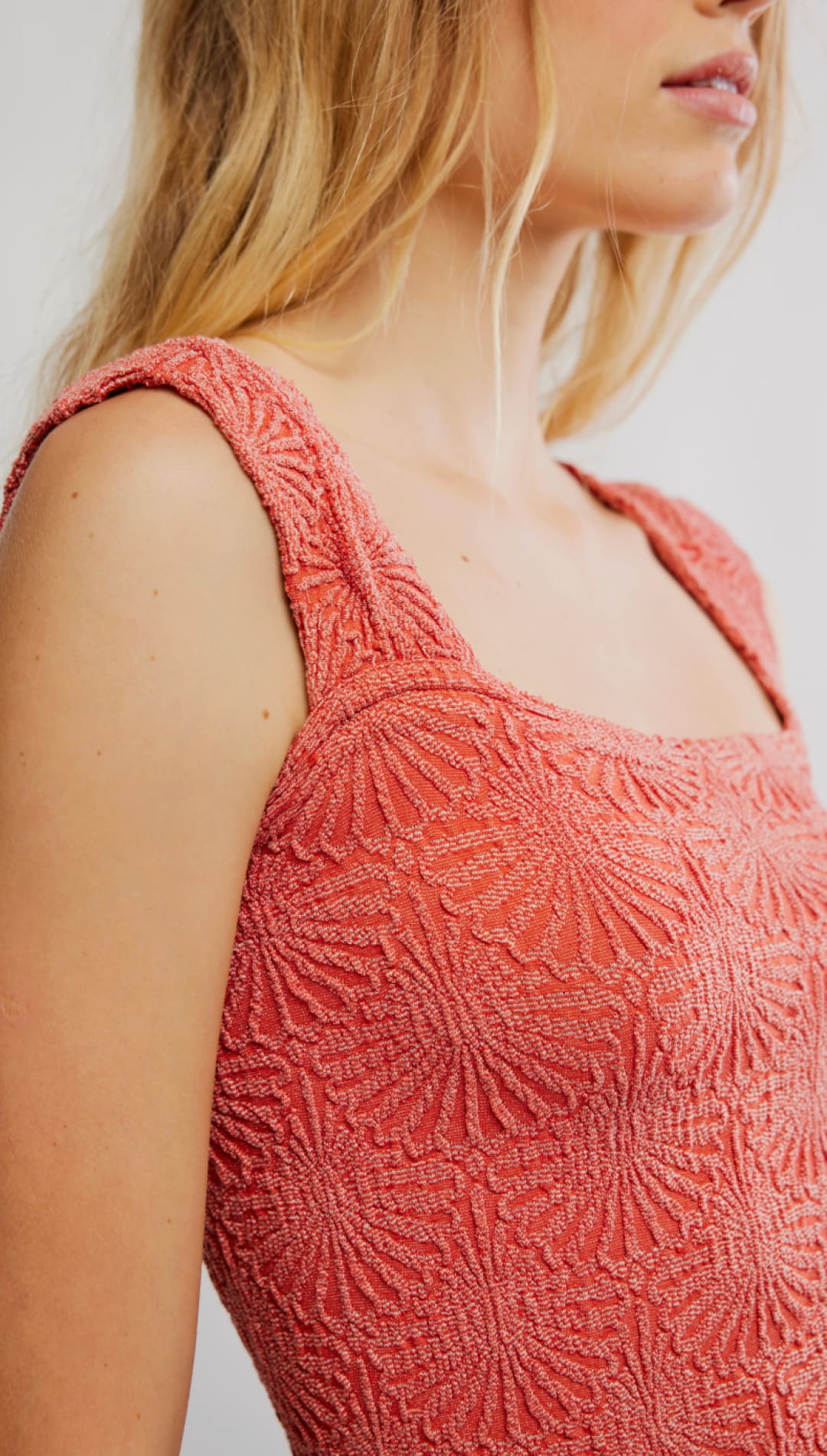 A coral-colored, textured knit top with a square neckline and wide shoulder straps.