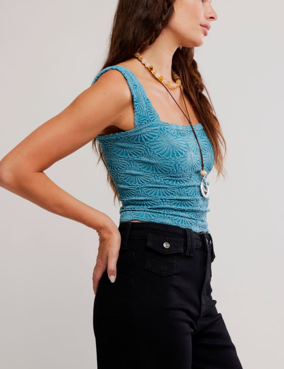 A teal, textured crochet crop top with square neckline and thin straps.