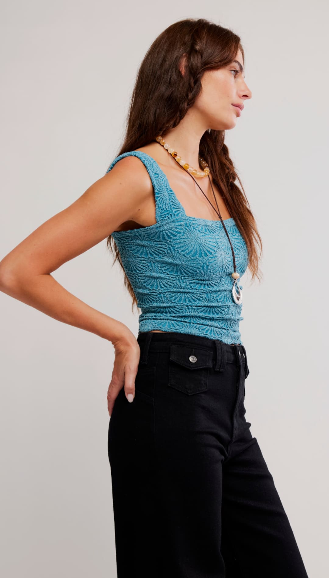 A teal, textured crochet crop top with square neckline and thin straps.