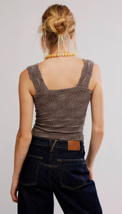A textured, dark brown sleeveless top with a subtle geometric pattern and ruched detailing at the waist.