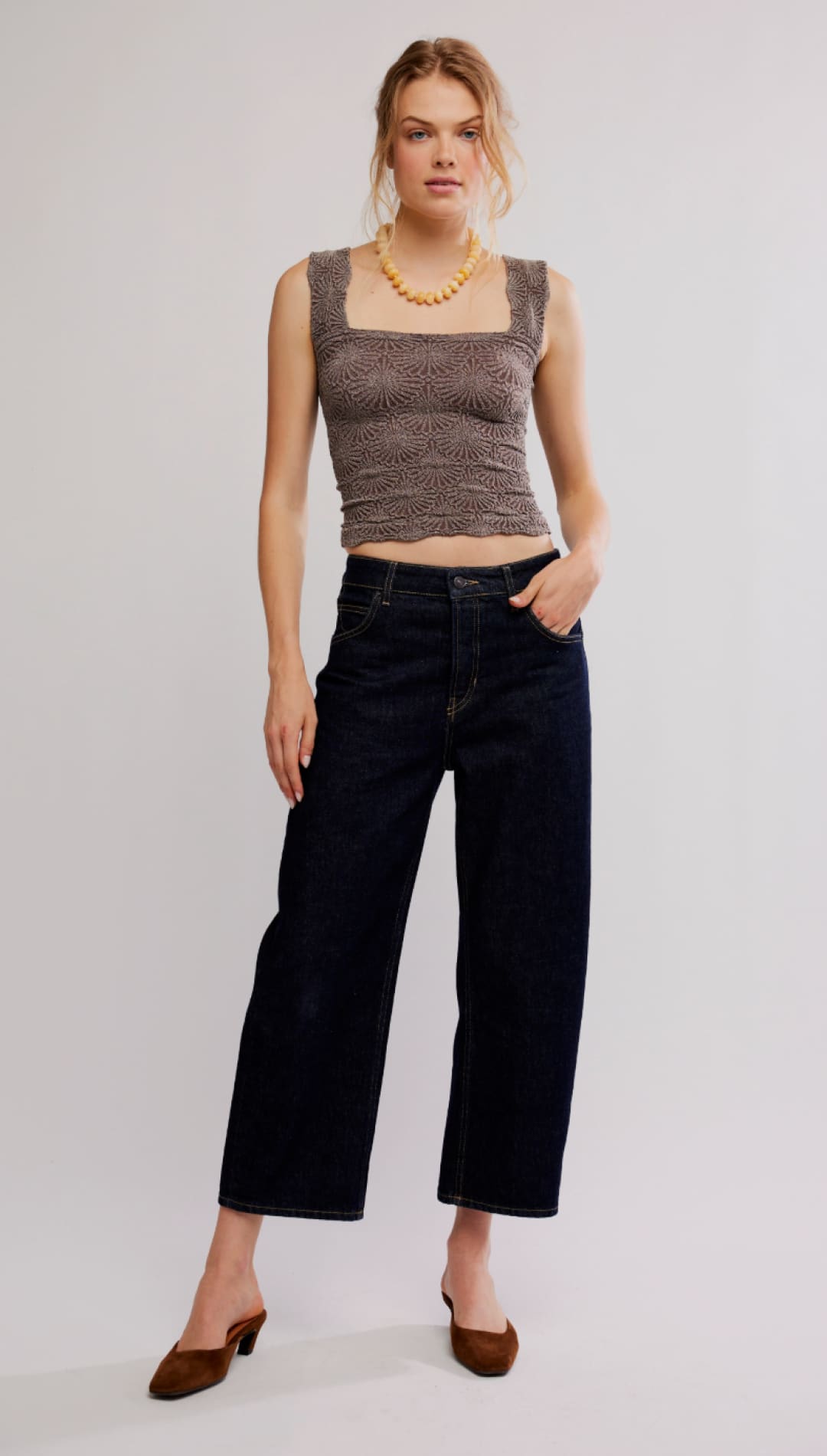 A woman wears a brown, textured crop top with square neckline and sleeveless design.