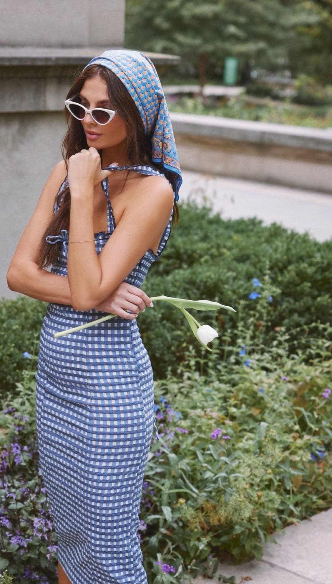 Woman in blue gingham dress and headscarf.