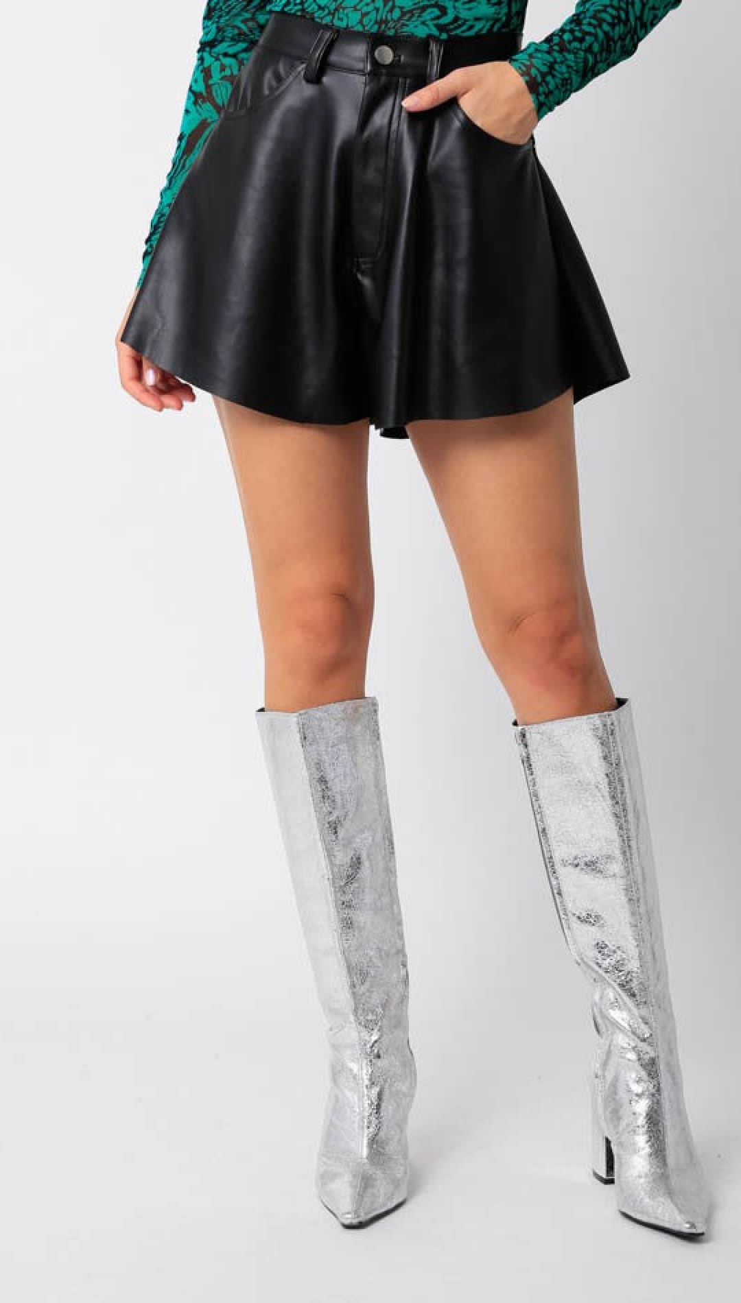 Women’s black faux leather flared shorts with silver knee-high boots.